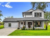Charming two-story home featuring a welcoming front porch with rocking chairs and landscaped front yard at 10901 Island Grove Rd, Clermont, FL 34711