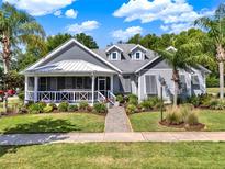 Charming single-story home featuring a inviting front porch, beautiful landscaping and mature palm trees at 1172 Fiesta Key Cir, Lady Lake, FL 32159