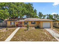 Charming single-story home with yellow paint, a red front door, an attached garage, and a well-manicured lawn at 2252 Kent Rd, Deltona, FL 32738