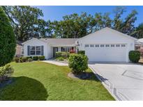 Charming single-story home with well-manicured lawn, mature trees, and a two-car garage at 2482 Ansley Path, The Villages, FL 32162