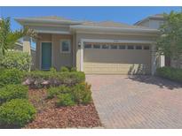 Charming single-story home featuring a brick driveway, lush landscaping, and a two-car garage at 2721 Picasso Ct, Kissimmee, FL 34743