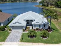 Beautiful lakefront home with lush lawn, mature landscaping, and charming paver driveway at 3723 Belle Rose Dr, Leesburg, FL 34748