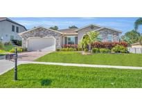 Beautiful single-story home with stone accents, lush landscaping, and a well-manicured lawn at 4060 Longbow Dr, Clermont, FL 34711