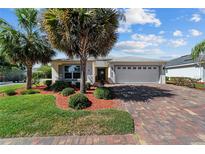 Charming single-story home with a brick driveway, mature landscaping, and a two-car garage at 4972 Big Cypress St, Oxford, FL 34484