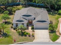 Beautifully landscaped home featuring a well-manicured lawn, mature trees, and an attached two-car garage at 760 Hammond Pl, The Villages, FL 32162