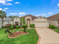 Charming single-story home featuring a meticulously landscaped yard, beige stucco, and a spacious two-car garage at 17930 Se 87Th Bourne Ave, The Villages, FL 32162
