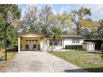 Charming single-story home with attached carport, basketball hoop, and a well-manicured front lawn at 25519 Colmar Ave, Sorrento, FL 32776