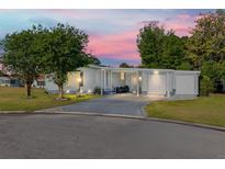 Charming single-story home with a well-maintained lawn, attached garages, and a long driveway at 728 Tangerine Dr, The Villages, FL 32159