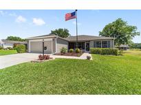 Charming single-story home featuring an American flag, well-maintained lawn and attached garage at 929 Eastmont Ct, The Villages, FL 32162