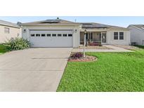 Charming single-story home features a well-manicured lawn, screened porch, two-car garage and solar panels at 9621 Se 168Th Maplesong Ln, The Villages, FL 32162