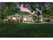 Beautifully landscaped single-Gathering home with stone accents, red door and mature trees in a serene setting at 10851 Lantana Crst, Clermont, FL 34711
