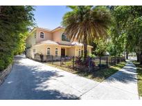 Charming two-story home with a beautiful yard, mature landscaping, and a black metal fence at 1196 Lakeshore Dr, Mount Dora, FL 32757