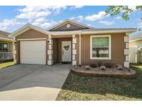 Inviting single-story home with a well-manicured lawn, attached garage, and charming front door wreath at 12340 Ne 48Th Loop, Oxford, FL 34484