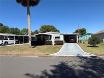 Charming single-story home featuring a well-kept lawn and a shaded carport on a sunny day at 1616 Lauren Ln, Lady Lake, FL 32159