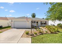 Charming single-story home featuring a well-manicured lawn and an attached two-car garage at 17076 Se 96Th Chapelwood Cir, The Villages, FL 32162