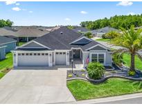Charming single-story home boasts a three-car garage and beautifully landscaped front yard with a palm tree at 2006 Oppenheimer Ct, The Villages, FL 34762