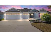Charming home showcasing a well-manicured lawn, two-car garage, and a welcoming entrance at 2006 Oppenheimer Ct, The Villages, FL 34762