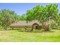 Charming home exterior featuring a well-manicured lawn, mature trees, and a welcoming garden trellis entrance at 2112 Robie Ave, Mount Dora, FL 32757