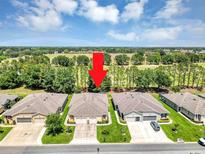 Features a well-maintained house on a manicured lawn with golf course in the background on a sunny day at 26951 White Plains Way, Leesburg, FL 34748