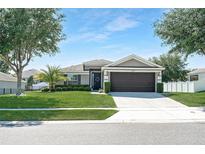Charming single-story home featuring a well-manicured lawn, mature trees, and a two-car garage at 274 Giovani Blvd, Clermont, FL 34715