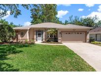Charming single-story home with manicured lawn, mature trees, and two car garage at 5209 Grove Mnr, Lady Lake, FL 32159
