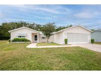 Charming single-story home featuring a two-car garage, well-maintained lawn, and mature landscaping at 10683 Se 174Th Loop, Summerfield, FL 34491