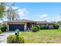 Charming single-story brick home featuring a well-maintained lawn, mature shrubs, and an attached garage at 16 Pine Run, Haines City, FL 33844
