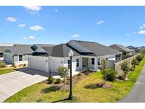 Beautiful single-story home with a large, attached three car garage and manicured lawn at 1674 Cadorette Dr, The Villages, FL 34762