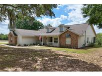 Charming single-Gathering home with brick accents, dormer windows, and a cozy front porch with white railing at 17728 Palm View Cir, Mount Dora, FL 32757