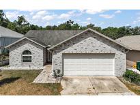 Charming brick home featuring an attached two-car garage and well-maintained landscaping at 38 Townhill Dr, Eustis, FL 32726