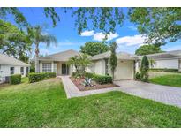 Charming single-story home with a well-manicured lawn, lush landscaping, and a brick driveway at 4167 Capland Ave, Clermont, FL 34711