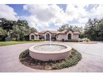 Stunning single-story home featuring a circular driveway with fountain, lush landscaping, and an inviting entrance at 5495 County Road 125, Wildwood, FL 34785