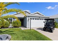 A well-maintained single-story home featuring a two-car garage and an adjacent golf cart at 1633 Manserra St, The Villages, FL 32163