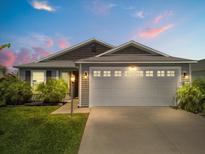 Charming single-story home featuring a two-car garage, manicured lawn, and well-lit exterior at 1633 Manserra St, The Villages, FL 32163