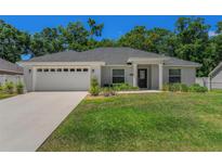 Charming single-story home features a manicured lawn, two car garage, and inviting front porch columns at 16380 Se 84Th Ct, Summerfield, FL 34491