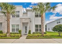 Charming two-story townhome with a modern stone facade and tropical landscaping at 17519 Hidden Forest Dr, Clermont, FL 34714