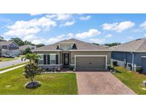 Charming front exterior showcasing a well-manicured lawn and a brick driveway at 456 Winter Solstice Ln, Mount Dora, FL 32757