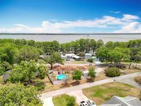 An inviting home with a sparkling blue pool, nestled amid lush greenery with a scenic lake view beyond at 1001 N Lakeshore Blvd, Howey In The Hills, FL 34737