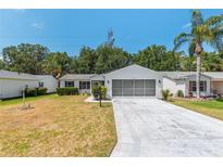 Charming single-story home with a well-maintained lawn, attached garage, and lush landscaping at 1212 Chaparral Dr, Lady Lake, FL 32159