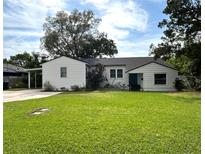 Charming single-story home with a well-manicured lawn and a covered carport to the side at 1414 Margate Ave, Orlando, FL 32803