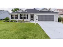 Charming single-story home featuring a well-manicured lawn, screened garage, and inviting front entrance at 17036 Se 79Th Clearview Ave, The Villages, FL 32162