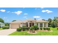 Charming single-story home featuring a well-manicured lawn, two car garage and attractive landscaping at 1875 Saybrook Way, The Villages, FL 32162