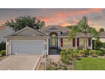 Charming single-story home with tan siding, red shutters, well-manicured landscaping, and two-car garage at 2139 Kaylee Dr, The Villages, FL 32162
