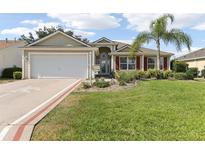 Well-maintained home featuring a two-car garage, lush lawn, and beautifully landscaped front yard at 2139 Kaylee Dr, The Villages, FL 32162