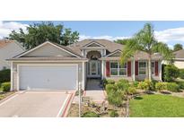 Charming single-Gathering home boasting a well-manicured lawn, red shutters, and an attached two-car garage at 2139 Kaylee Dr, The Villages, FL 32162