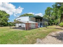 Spacious home with an attached awning, open carport and a large screened-in outdoor living space at 300 Carol Ann Dr, Edgewater, FL 32132