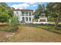 Elegant two-story white home with a charming veranda and lush landscaping on a well-maintained lawn at 6905 Clayton St, Mount Dora, FL 32757