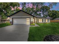 Charming single-Gathering home featuring a modern garage door and well-manicured lawn and landscaping at 10033 Canterbury Dr, Leesburg, FL 34788