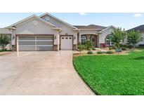 Charming single-story home featuring a well-manicured lawn, beautiful landscaping, and a spacious driveway at 10977 Se 169Th Ln, Summerfield, FL 34491