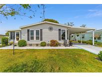 Charming single story home featuring green lawn, carport, landscaped garden, and decorative facade at 1109 Paradise Dr, The Villages, FL 32159